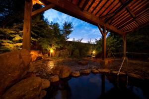 a night view of a pond under a pavilion at 由布院ユウベルホテル in Yufuin