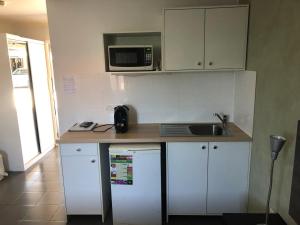 a kitchen with a sink, microwave and refrigerator at Mackay Motor Inn in Mackay