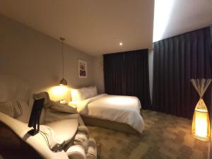 a hotel room with two beds and a couch at Brown Dot Hotel Jinju in Jinju