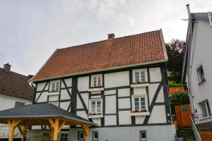 un bâtiment noir et blanc avec des fleurs sur les fenêtres dans l'établissement ALTES ZOLLHAUS der Burg Hachen, 