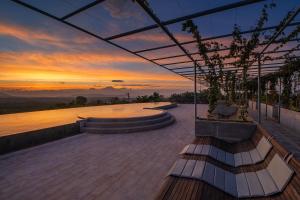 d'une terrasse avec un banc et un coucher de soleil en arrière-plan. dans l'établissement Sumberkima Hill Retreat 2, à Pemuteran