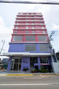 een hoog gebouw met een rood en paars bij MySpace Hotel Comembo Taguig in Manilla