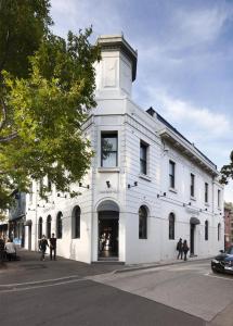 biały budynek z wieżą zegarową na ulicy w obiekcie Coppersmith Hotel w Melbourne