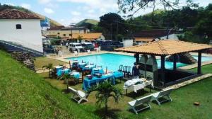 una gran piscina con mesas y sillas azules en HOTEL SACRA FAMILIA -15 Km da Terra dos Dinos en Sacra Família do Tinguá