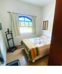 Schlafzimmer mit einem Bett und einem Fenster in der Unterkunft HOTEL SACRA FAMILIA -15 Km da Terra dos Dinos in Sacra Família do Tinguá