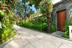 a concrete walkway leading to a house with a tree at Sun Island Boutique Villas & Spa Seminyak in Seminyak