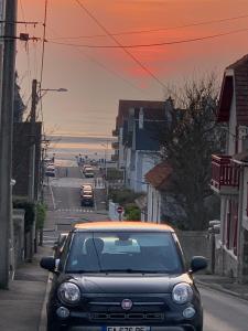 une voiture garée dans une rue avec l'océan en arrière-plan dans l'établissement Entre mer et commerces, à Wimereux