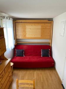 a red couch with two pillows on it in a room at Studio Font-Romeu avec place de parking in Font-Romeu-Odeillo-Via