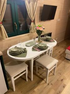 una mesa blanca con sillas y un jarrón de flores en La roulotte de bonneval, en Charleval
