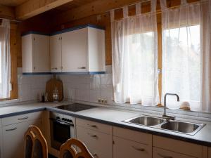 a kitchen with white cabinets and a sink and two windows at Ferienhaus Friedrichsblick in Lug