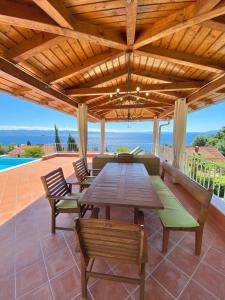 a wooden table and chairs on a patio with the ocean at VILLA LOVRAN - 150m to the beach - infinity pool - incredible sea view - Fitnessraum in Lovran