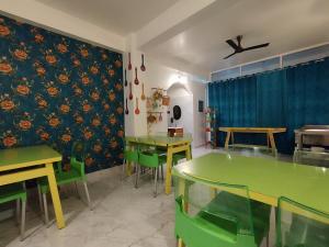 une salle à manger avec des tables vertes et des rideaux bleus dans l'établissement Jubels Homestay, à Guwahati