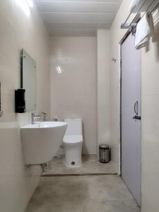 a white bathroom with a sink and a toilet at Jubels Homestay in Guwahati