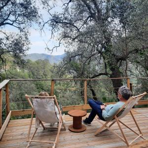 Ein Mann und eine Frau, die auf einem Deck auf Stühlen sitzen in der Unterkunft Chalet Zenitude in Breil-sur-Roya