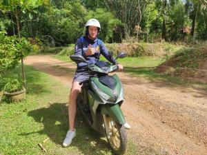 a man sitting on a motorcycle on a dirt road at Suan Bang Bon Guest House in Plai Phraya