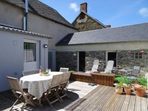 a patio with a table and chairs on a deck at Stone House in Bricqueville near Sandy Beach in Bricqueville-sur-Mer