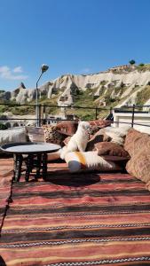 a bench with pillows and a table on a rug at Salkım Cave House in Göreme