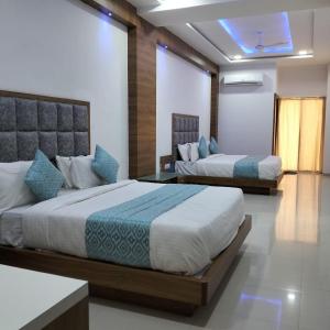 a bedroom with two beds and a window with a tv at Hotel Neptune Palace in Anand