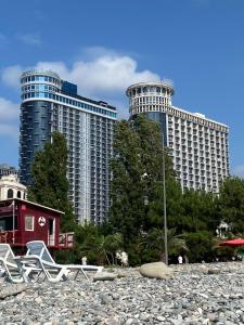 a beach with chairs and two tall buildings at Batumi - Orbi Sea Tower & Residence in Batumi
