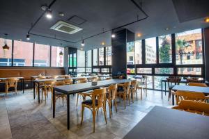 a restaurant with tables and chairs and large windows at Hotel Haema in Jeju