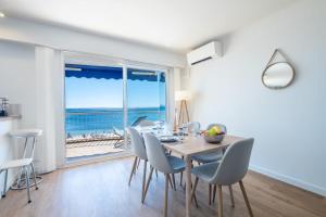 a dining room with a table and chairs with a view of the ocean at SERRENDY Renovated apartment with sea view in Cannes