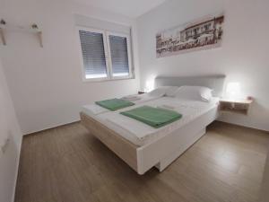 a white bedroom with a bed and two windows at Lovely one bedroom apartment in Ub