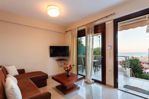 een woonkamer met een bank, een tv en een balkon bij Seaside Getaway - Aelia Villa's Dreamy Paradise in Petalidhion