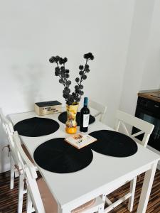 Una mesa blanca con una botella de vino y flores. en Apartament in regim hotelier King Medias, en Mediaş