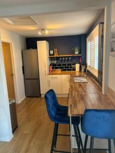 cocina con mesa de madera y sillas azules en Unique one bedroom guest house with free parking, en Aldershot