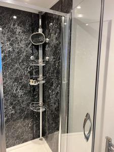 a shower stall with a glass door with a shower at Unique one bedroom guest house with free parking in Aldershot