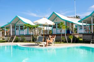 duas mulheres sentadas em cadeiras ao lado de uma piscina em Le Pirate Gili Meno - Adults Only em Gili Meno