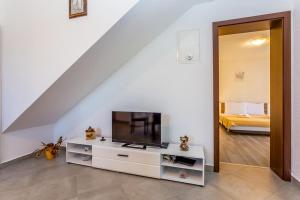 ein Wohnzimmer mit einem TV auf einem weißen Schrank in der Unterkunft Dvosobni apartman u kući s bazenom, 1 kat in Draga Bašćanska