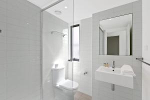 Baño blanco con lavabo y espejo en Sandy Beach Apt 6 en Lorne