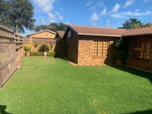 a yard with green grass in front of a house at Dobbs Lodge in Centurion