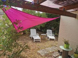 un patio con 2 sillas y una sombrilla rosa en Mobil home hors camping, en Roquebrune-sur-Argens