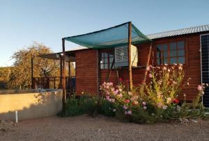 a wooden house with flowers in front of it at Jamais le même in Kakamas