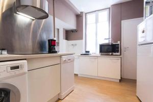 a large kitchen with white cabinets and appliances at La Petite Bourgogne in Dijon