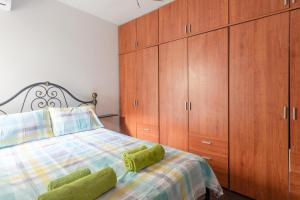 a bedroom with a bed with green pillows and wooden cabinets at Sea view apartment in St Paul's Bay in St. Paul's Bay