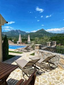 a patio with chairs and a pool and mountains at Eco Villas Merak in Virpazar
