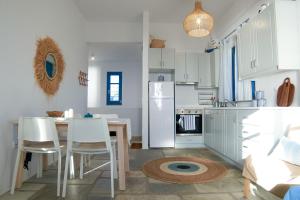 a kitchen with a table and white cabinets at Alas Residence Liotrivi Kythnos in Kithnos +23 photos