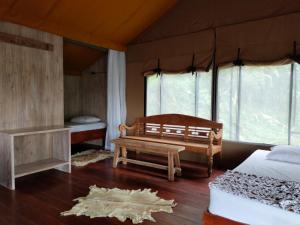 a room with two beds and a bench in a tent at Sang Giri - Mountain Glamping Camp in Jatiluwih
