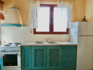 La cuisine est équipée de placards verts et d'un réfrigérateur blanc. dans l'établissement Anogeio - Traditional house in Tikhion, à Tíkhion
