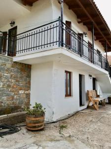 a white building with a balcony and a bench at Anogeio - Traditional house in Tikhion in Tíkhion