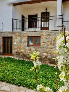 una casa de piedra con balcón y flores frente a ella en Anogeio - Traditional house in Tikhion en Tíkhion
