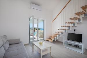- un salon avec un canapé, une télévision et des escaliers dans l'établissement Vila Blanka Apartments, à Rogoznica