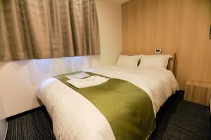 大阪的住宿－Tabist Hotel Asiato Namba，一间卧室配有一张带绿色和白色毯子的床