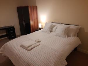 uma grande cama branca com lençóis e almofadas brancos em Queens One em Urmston