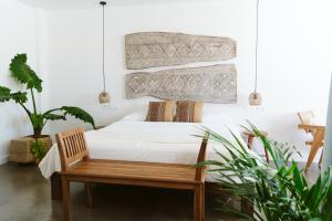 1 dormitorio con cama, banco y plantas en Dreamsea Surf House Fuerteventura, en Corralejo