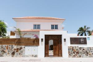 ein weißes Haus mit brauner Tür in der Unterkunft Dreamsea Surf House Fuerteventura in Corralejo