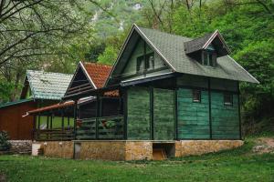 una gran casa verde con techo de gambrel en Vikendica,, Tadic,, Ovčar Banja, en Ovčar Banja